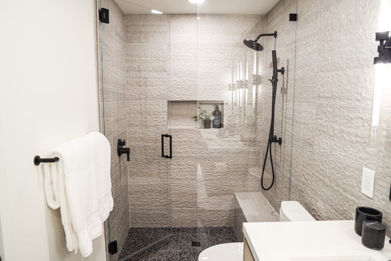 Black tile and a glass walk-in shower add a modern touch.