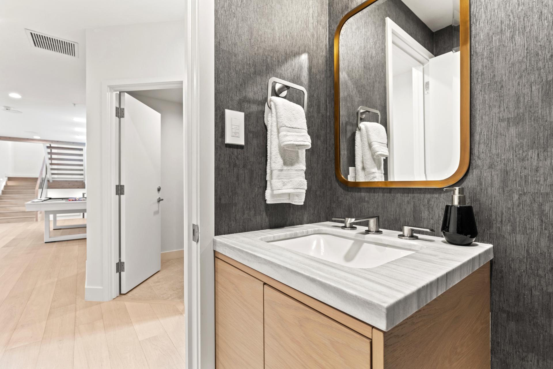Powder room on the lower level with warm lighting and a wood-trimmed mirror.