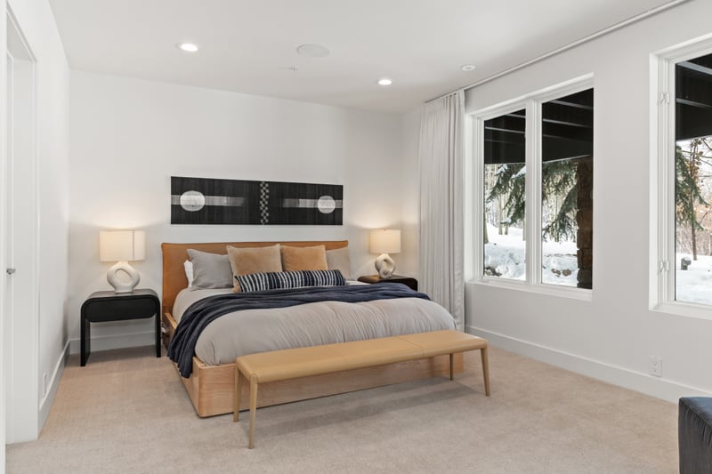Guest suite with King bed, TV, lounge space, and backyard-facing windows.