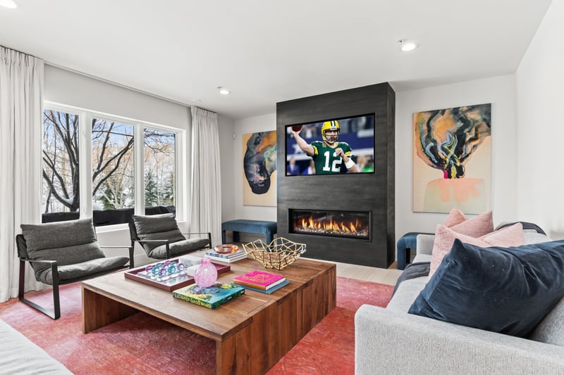 This vibrant family room offers colorful seating, a wall-mounted TV, and fireplace for laid-back moments.