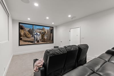 A private theater room with plush seating and projector system makes movie nights unforgettable.