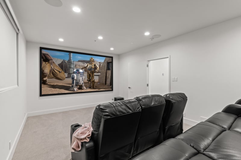 A private theater room with plush seating and projector system makes movie nights unforgettable.