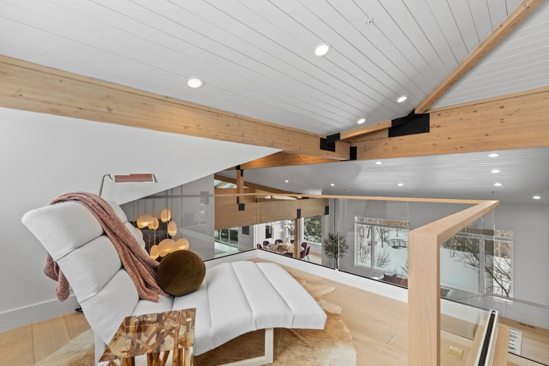 A bird’s-eye view of the living room reveals beautiful beams, floating stairs, and open-plan design.