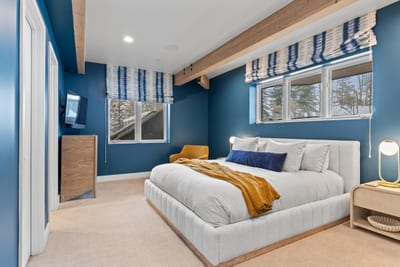 Guest bedroom with King bed and bold blue walls, offering privacy and natural light.