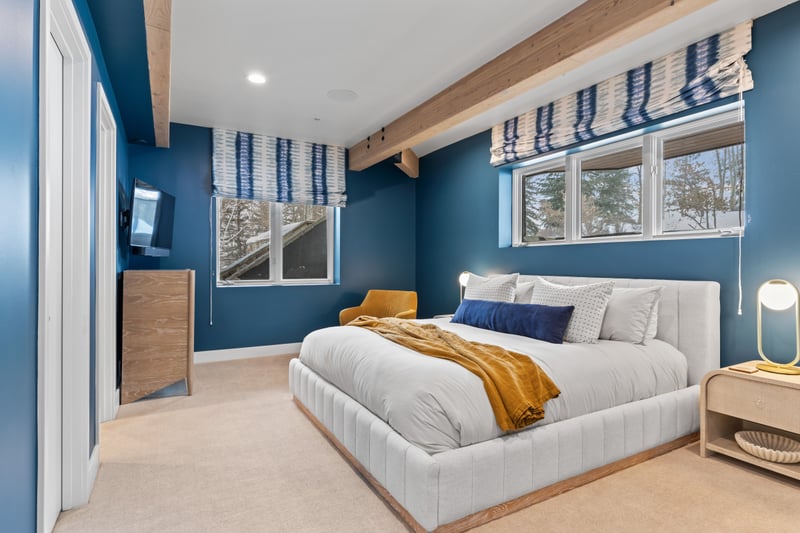 Guest bedroom with King bed and bold blue walls, offering privacy and natural light.