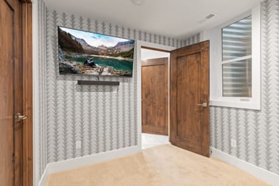 Another view of the bunk room with mounted TV and playful wallpaper.