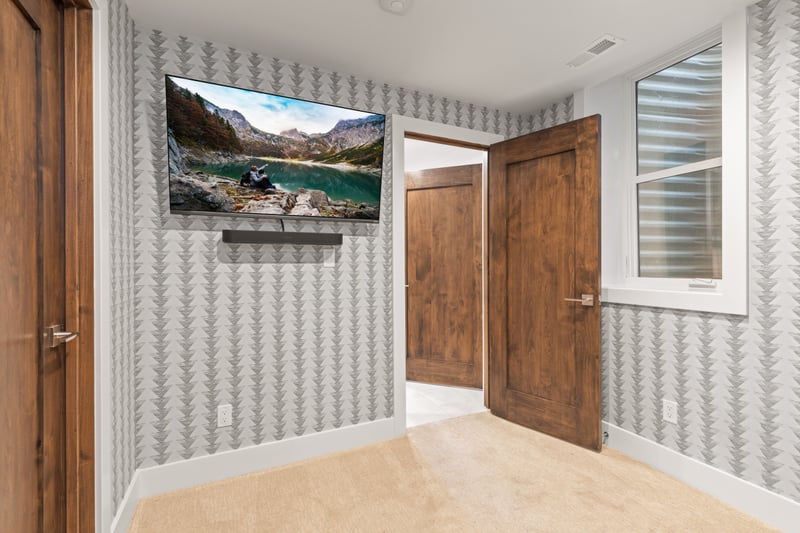 Another view of the bunk room with mounted TV and playful wallpaper.
