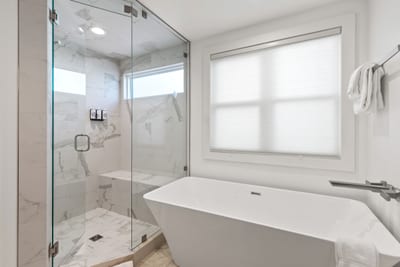 Your ensuite features a spa-style soaking tub, walk-in glass shower, and tile flooring. PEA-1009