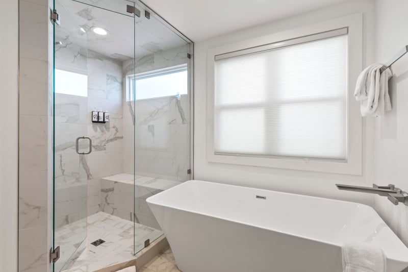 Your ensuite features a spa-style soaking tub, walk-in glass shower, and tile flooring. PEA-1009