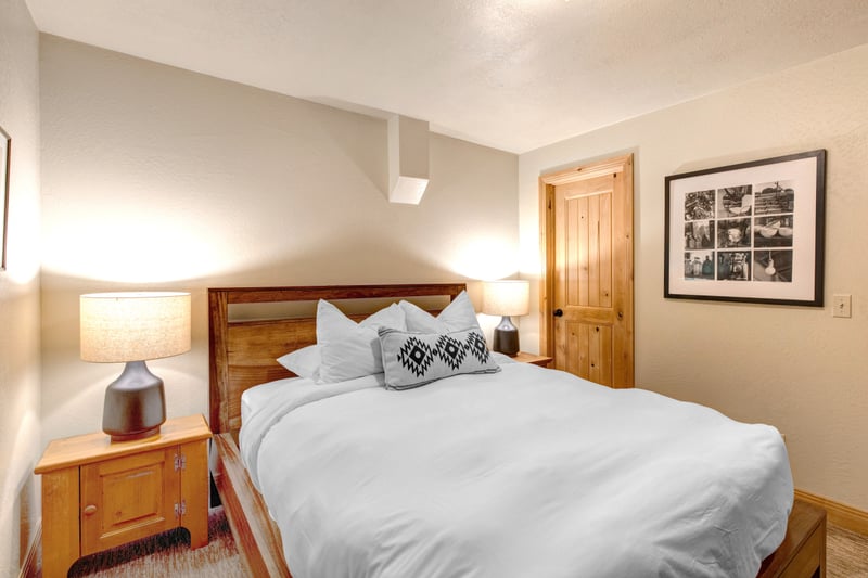 Another angle of the Queen guest room with warm lighting and bedside storage.