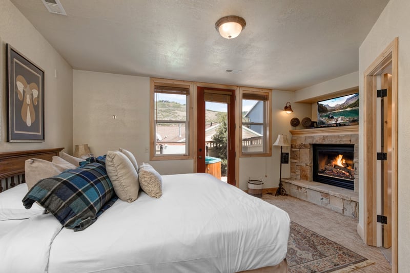 This King suite includes warm wood furnishings, a mounted TV, and a sitting area near the fireplace.