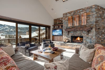 Vaulted ceilings, a stone fireplace, and wraparound windows create an impressive welcome in the great room.