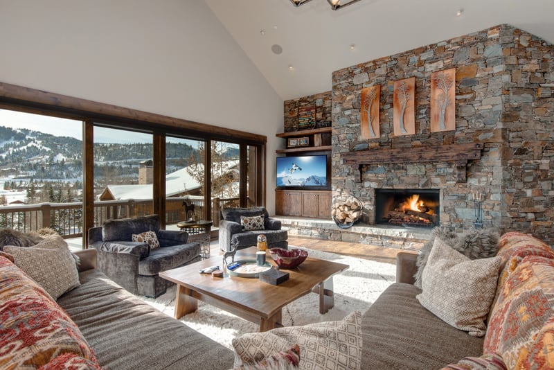 Vaulted ceilings, a stone fireplace, and wraparound windows create an impressive welcome in the great room.