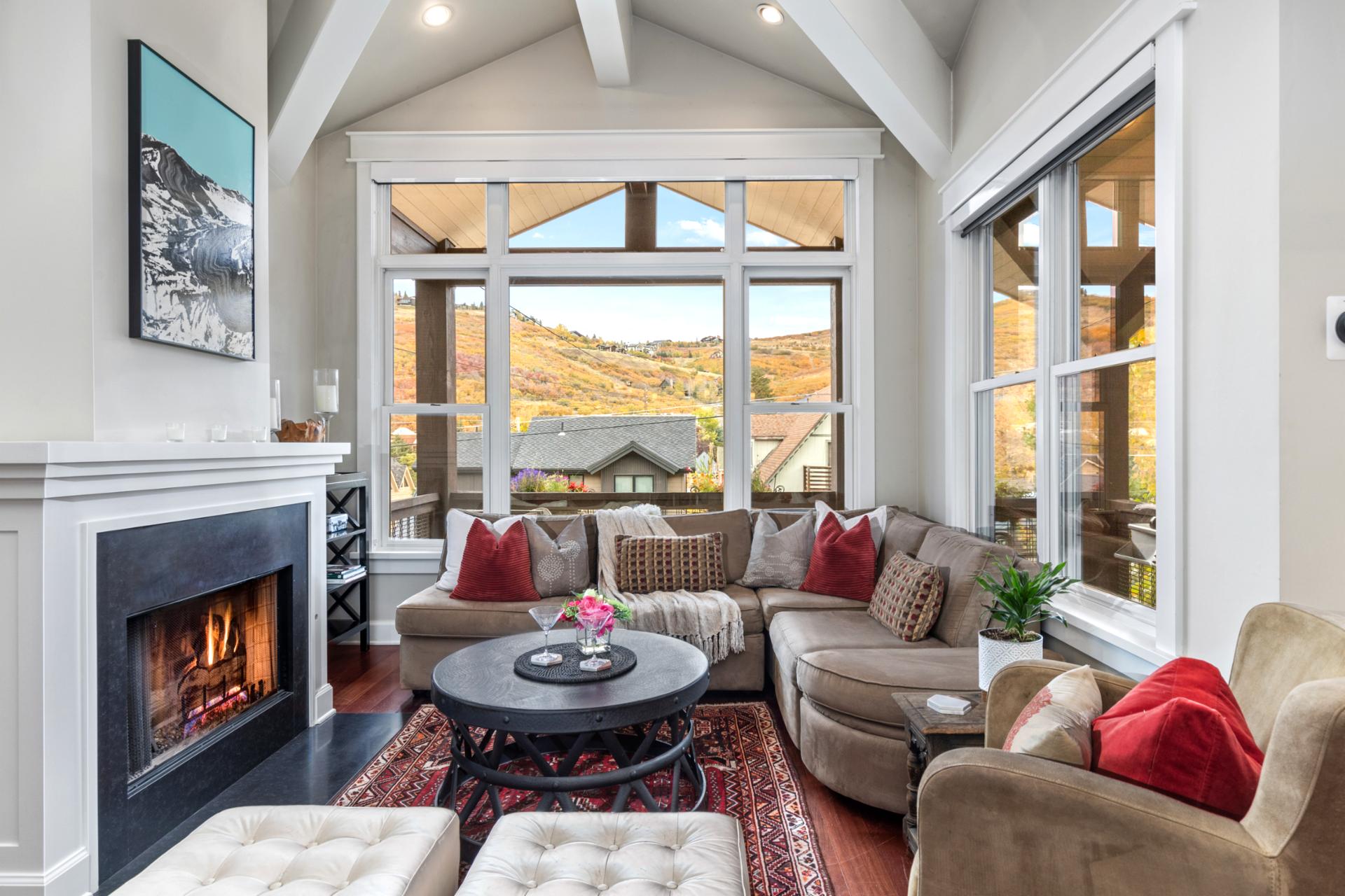 This second angle shows the open concept living with fireplace, vaulted ceiling, and balcony access.