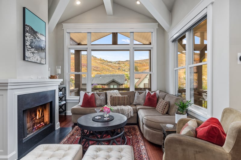 This second angle shows the open concept living with fireplace, vaulted ceiling, and balcony access.