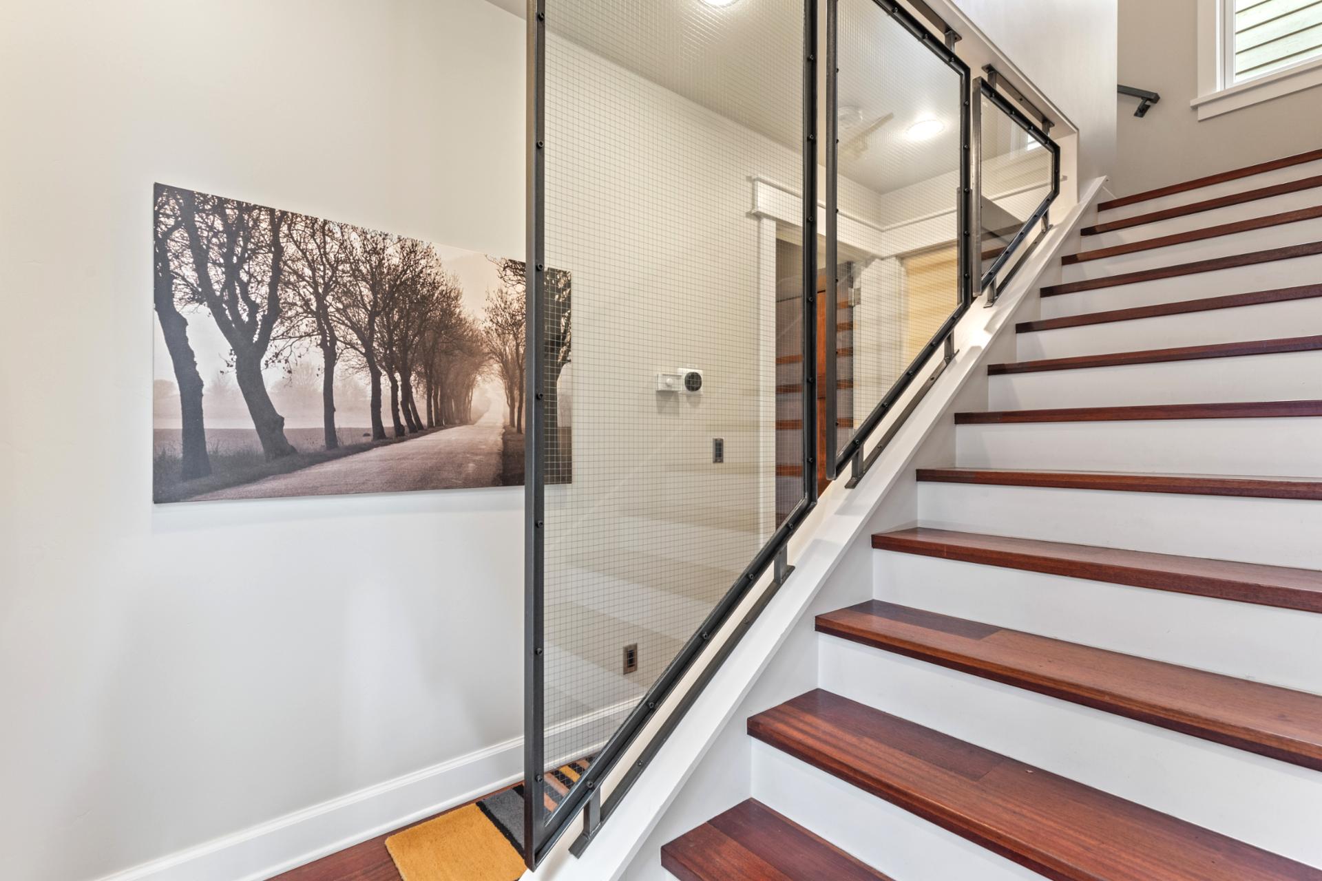 Modern glass railings and hardwood stairs connect both levels with sleek, open design.