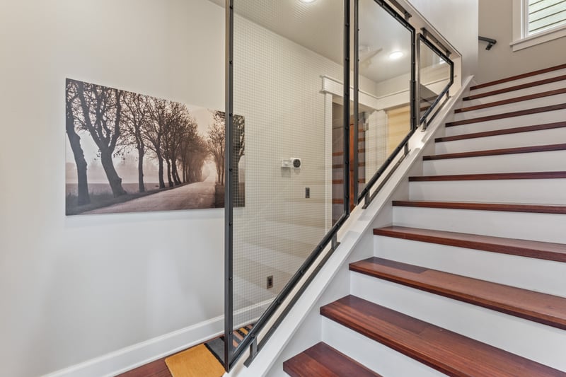 Modern glass railings and hardwood stairs connect both levels with sleek, open design.