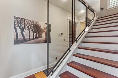 Modern glass railings and hardwood stairs connect both levels with sleek, open design.