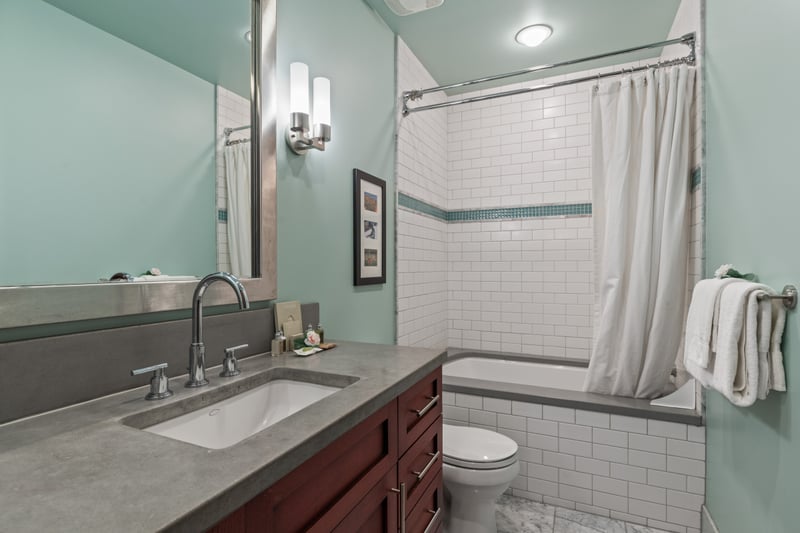 This bath includes a full-size tub and shower with modern tile.