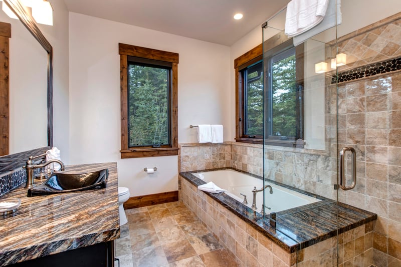 Soak in the deep tub or refresh in the walk-in shower, all framed by forest views and elegant natural stone finishes.