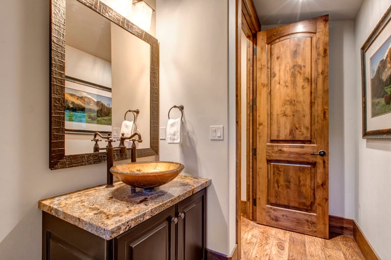 Elegant powder room with vessel sink and rich wood finishes.