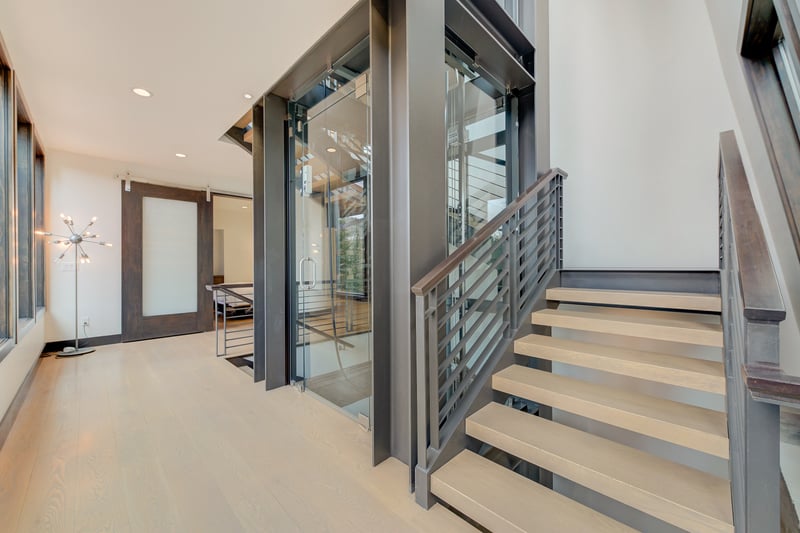 Glass railings and open stairs frame views through the double-height great room.