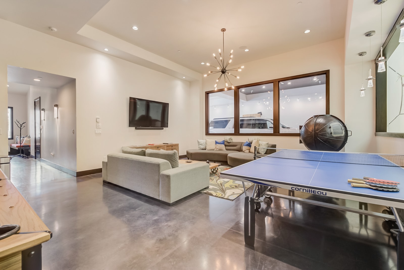 Lower-level entertainment room includes billiards, comfy seating, and a mounted TV.