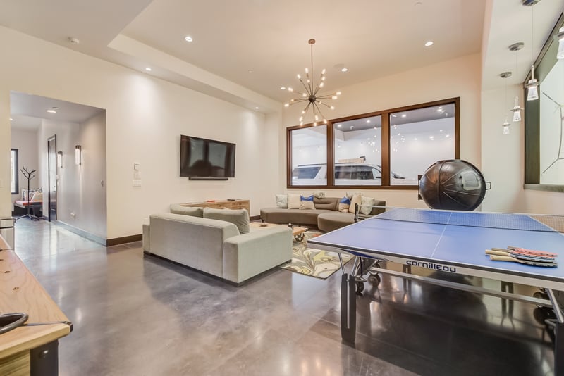 Lower-level entertainment room includes billiards, comfy seating, and a mounted TV.
