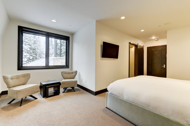 Bright corner room with mountain tree views, TV and simple, modern furnishings.