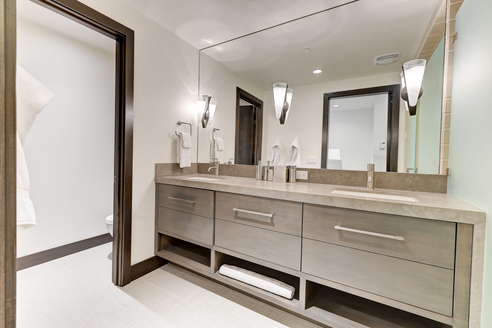Dual-sink vanity with backlit mirrors and clean design.