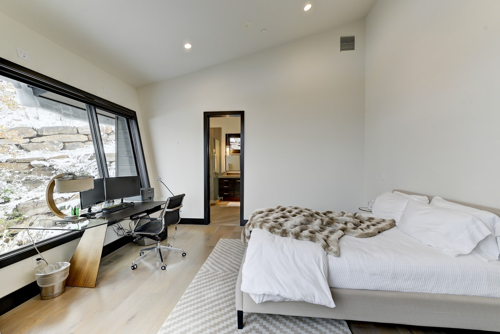 Queen bedroom with desk, reading chair, and sleek design for work or rest.