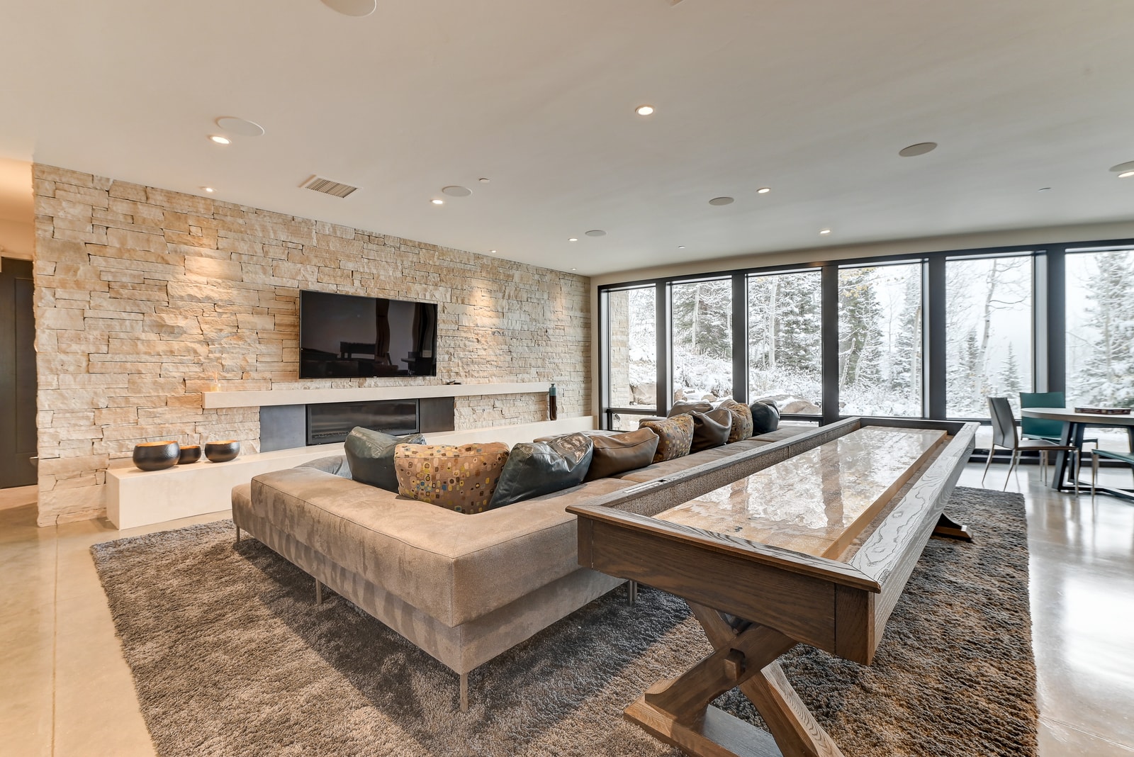 Family media zone flows into lower-level lounge with natural light and shuffleboard table.