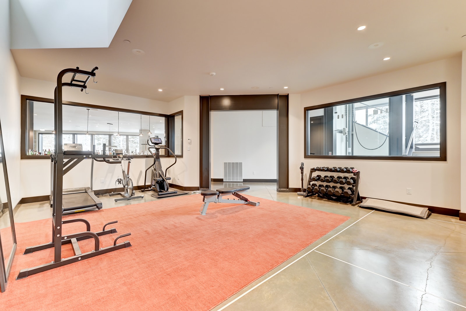 Gym area with equipment, TV, and windows for natural light.