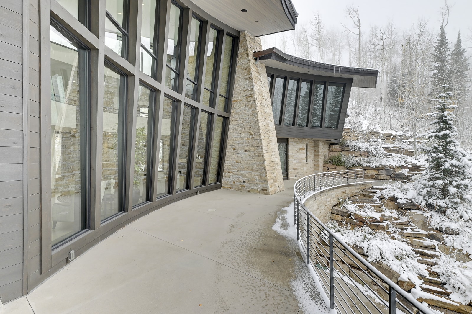 Curved balcony offers a peaceful perch above the snow-dusted forest.