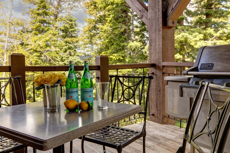 Enjoy drinks and grilled meals on the shaded balcony with forest backdrop.