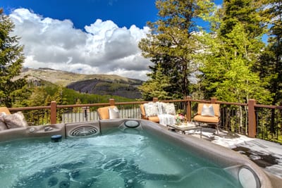This sunny deck features hot tub, mountain views, and room to gather.