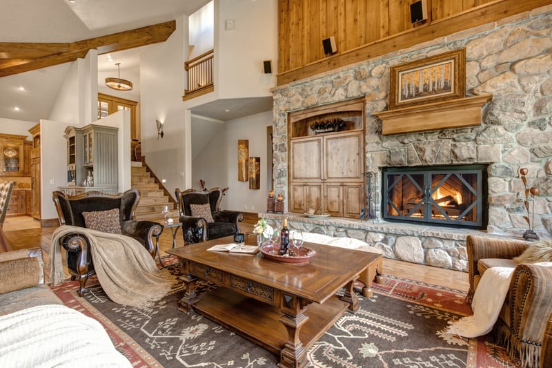 Gather beside the fireplace in this inviting space framed by large windows and timber details.