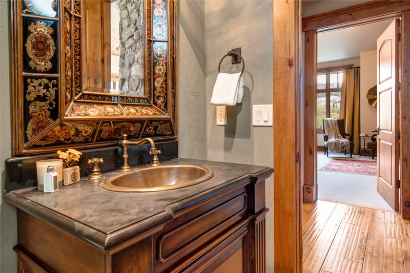 This elegant half bath features ornate wood accents, granite vanity, and mountain lodge flair.