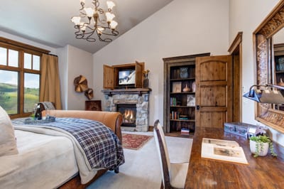 The main-level King suite blends comfort and elegance with a fireplace, writing desk, and mountain light.