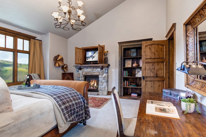 The main-level King suite blends comfort and elegance with a fireplace, writing desk, and mountain light.