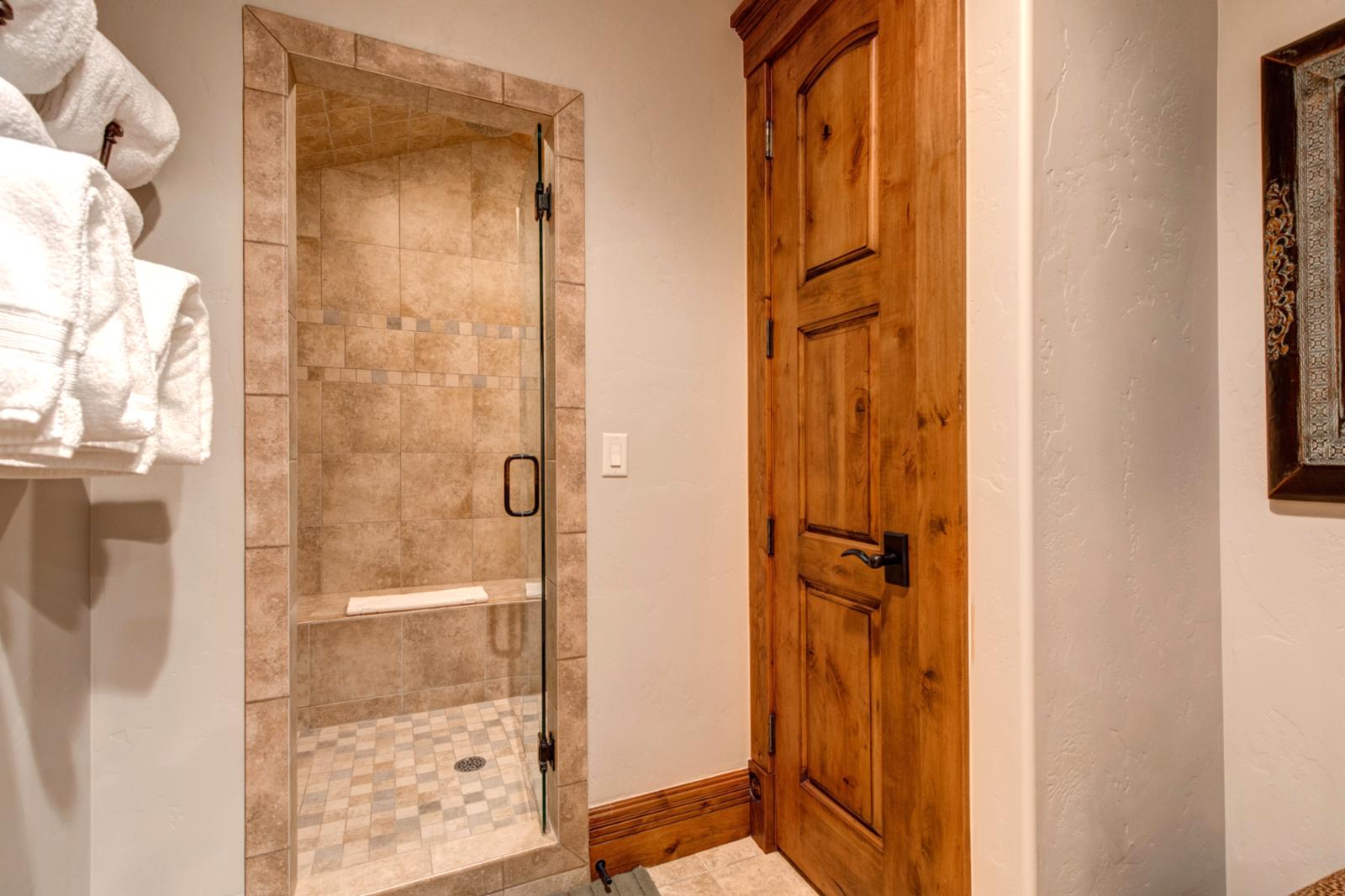Tiled walk-in shower and bench seating in the entertainment-level bath.