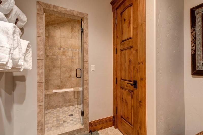 Guest bathroom with a glass-enclosed tiled shower, plush robes, and towels ready for arrival.