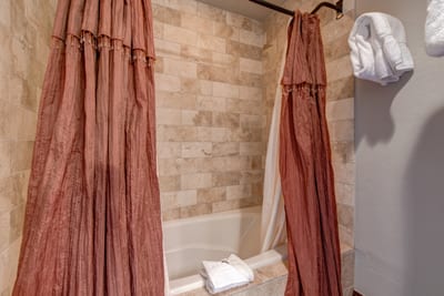 Combo tub and shower with soft tile tones and cozy curtain detail.