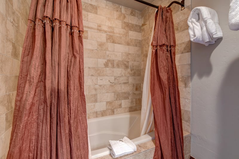 Combo tub and shower with soft tile tones and cozy curtain detail.