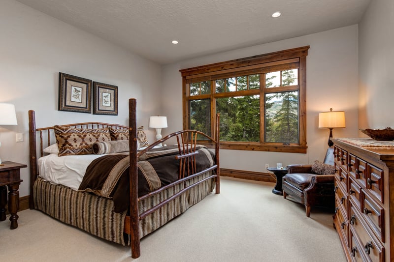 Lower-level King room with large window, lodge-style bed, and neutral palette.