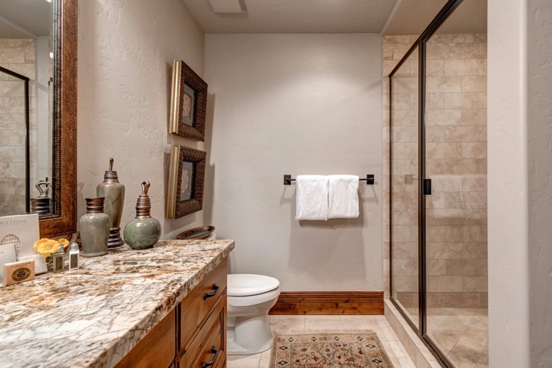 Glass walk-in shower, granite vanity, and tasteful art add comfort and charm.