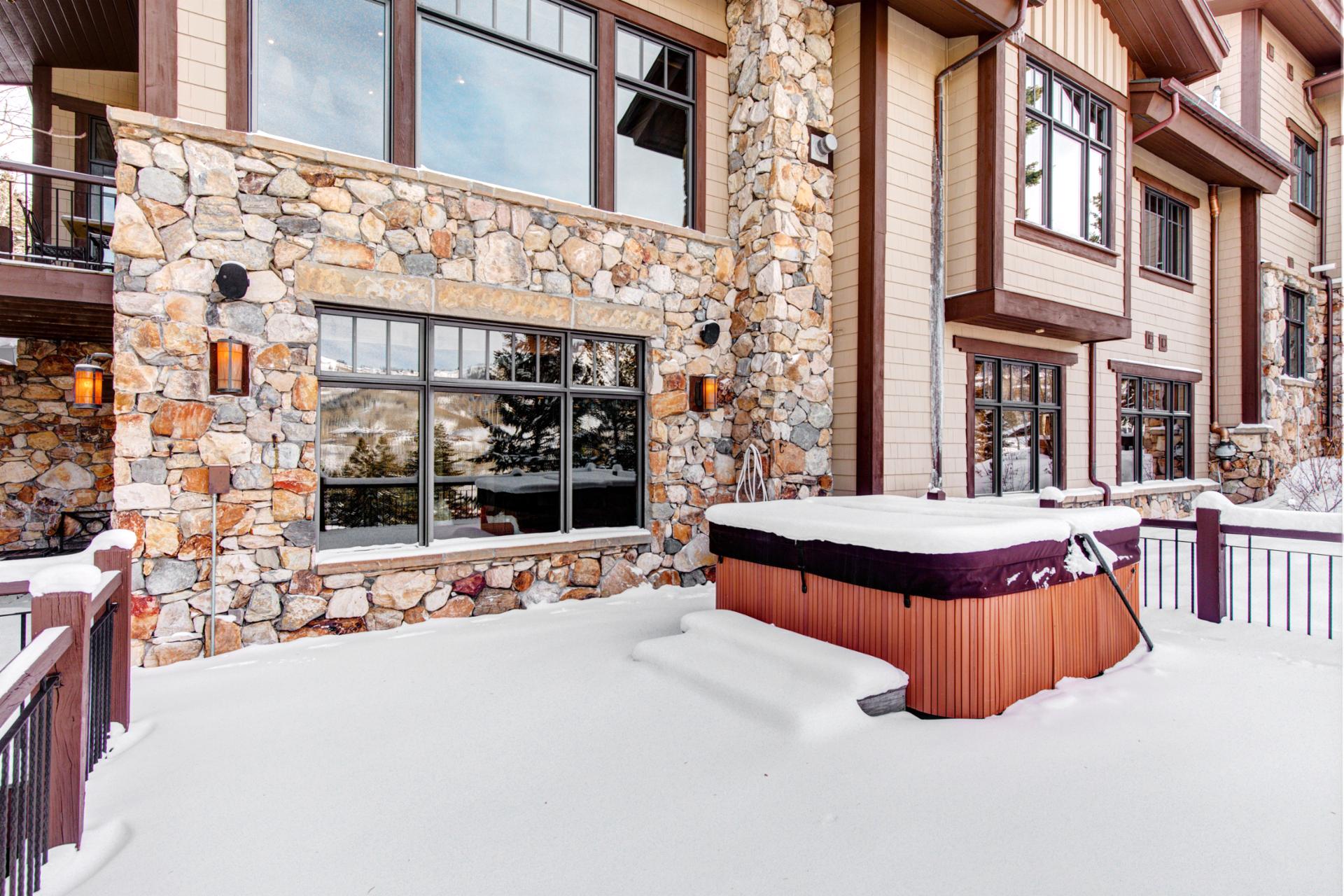 Rear view reveals three decks, stone accents, and direct hot tub access.