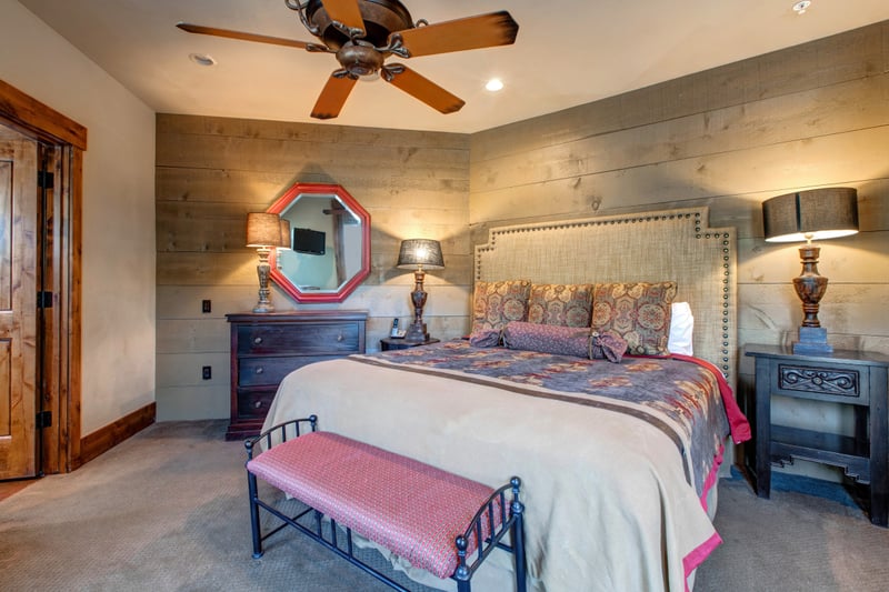 Guest Bedroom 4 features a King bed, rustic wood accent walls, and warm lighting for a cozy retreat on the main floor.
