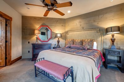 Guest Bedroom 4 features a King bed, rustic wood accent walls, and warm lighting for a cozy retreat on the main floor.