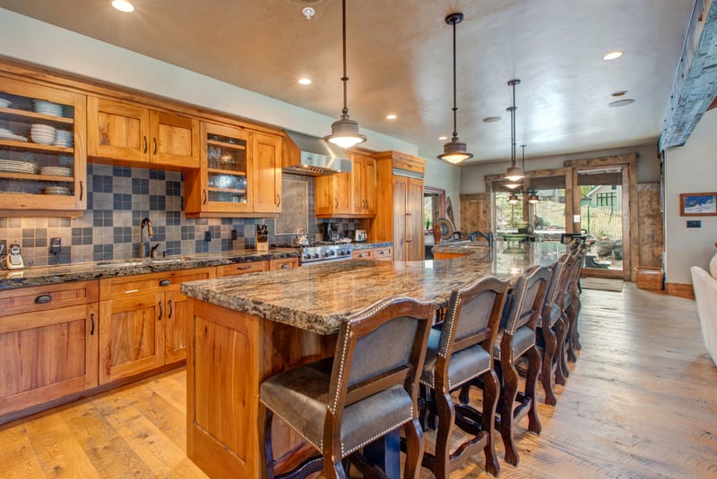 Gather around the granite island with seating for five, surrounded by warm wood cabinetry and rustic finishes.